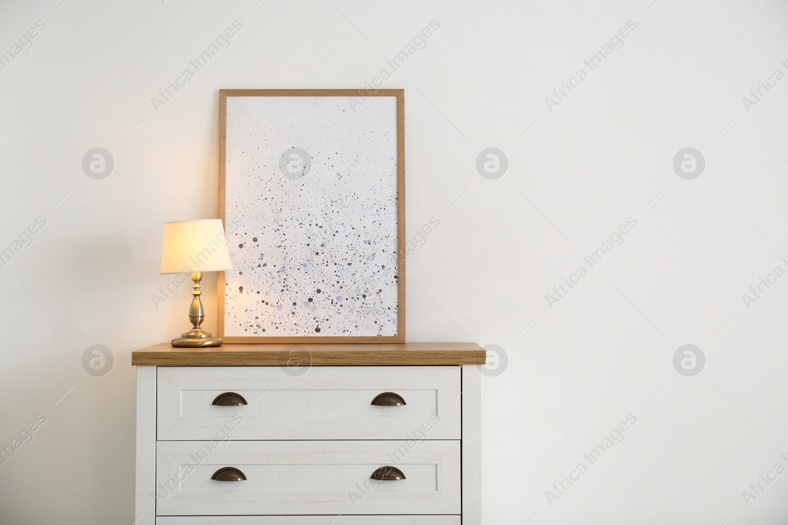 Photo of Stylish chest of drawers with lamp in living room