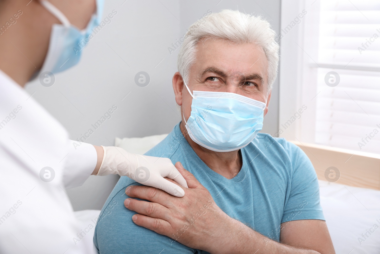 Photo of Doctor taking care of senior man with protective mask at nursing home