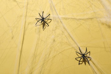 Photo of Cobweb and spiders on yellow background, top view