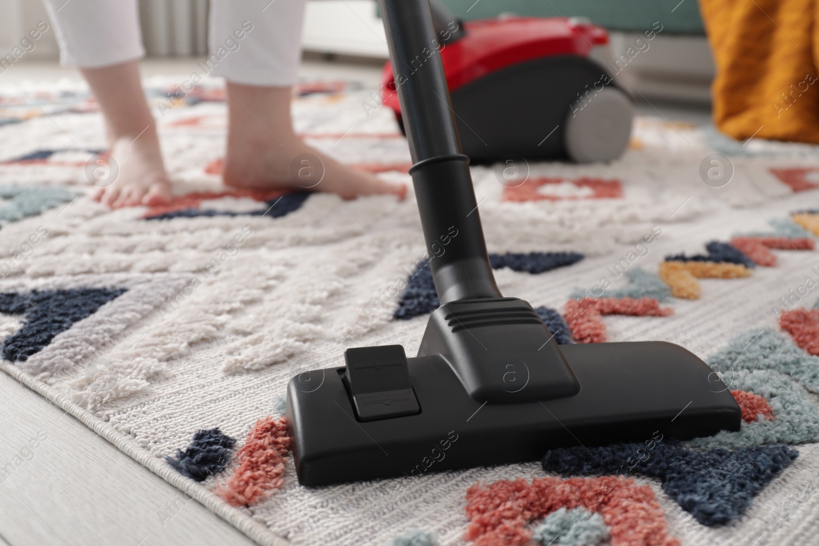 Photo of Woman cleaning carpet with vacuum cleaner at home, closeup. Space for text