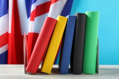 Photo of Learning foreign language. Different books on wooden table near flag of United Kingdom