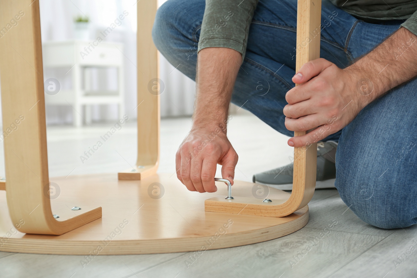 Photo of Young working man repairing table at home, closeup