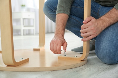 Photo of Young working man repairing table at home, closeup