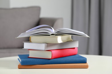 Photo of Stack of hardcover books on white table indoors, closeup