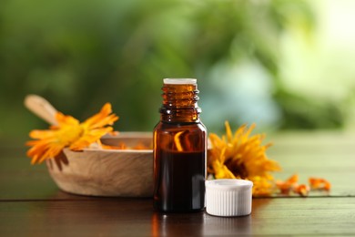 Photo of Bottle of essential oil with calendula extract on wooden table outdoors, closeup