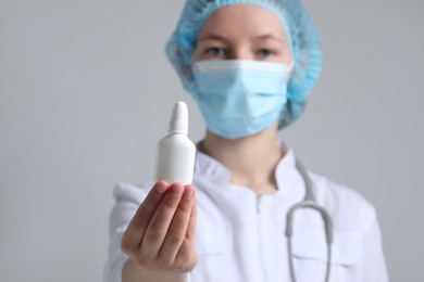 Photo of Doctor holding nasal spray on white background, selective focus