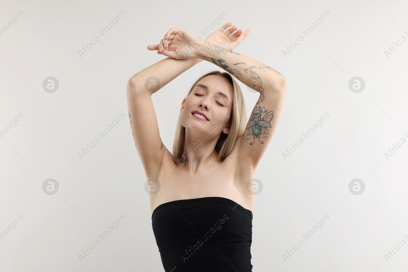 Photo of Portrait of beautiful tattooed woman on light background