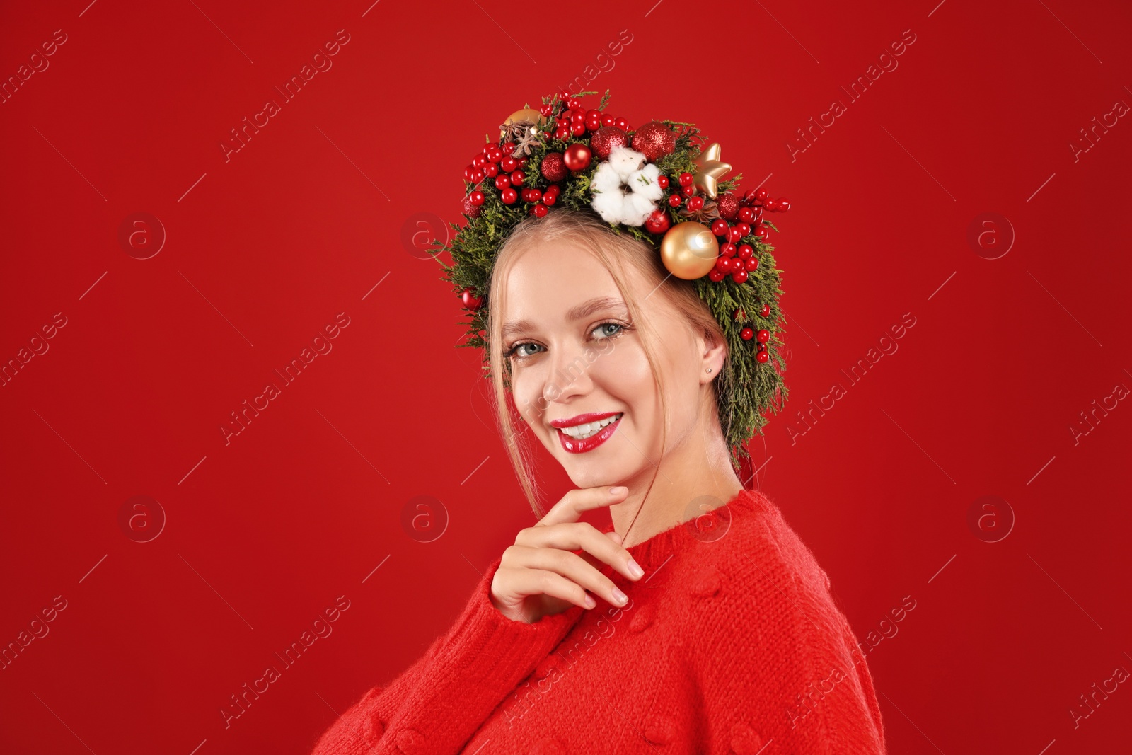 Photo of Beautiful young woman wearing Christmas wreath on red background