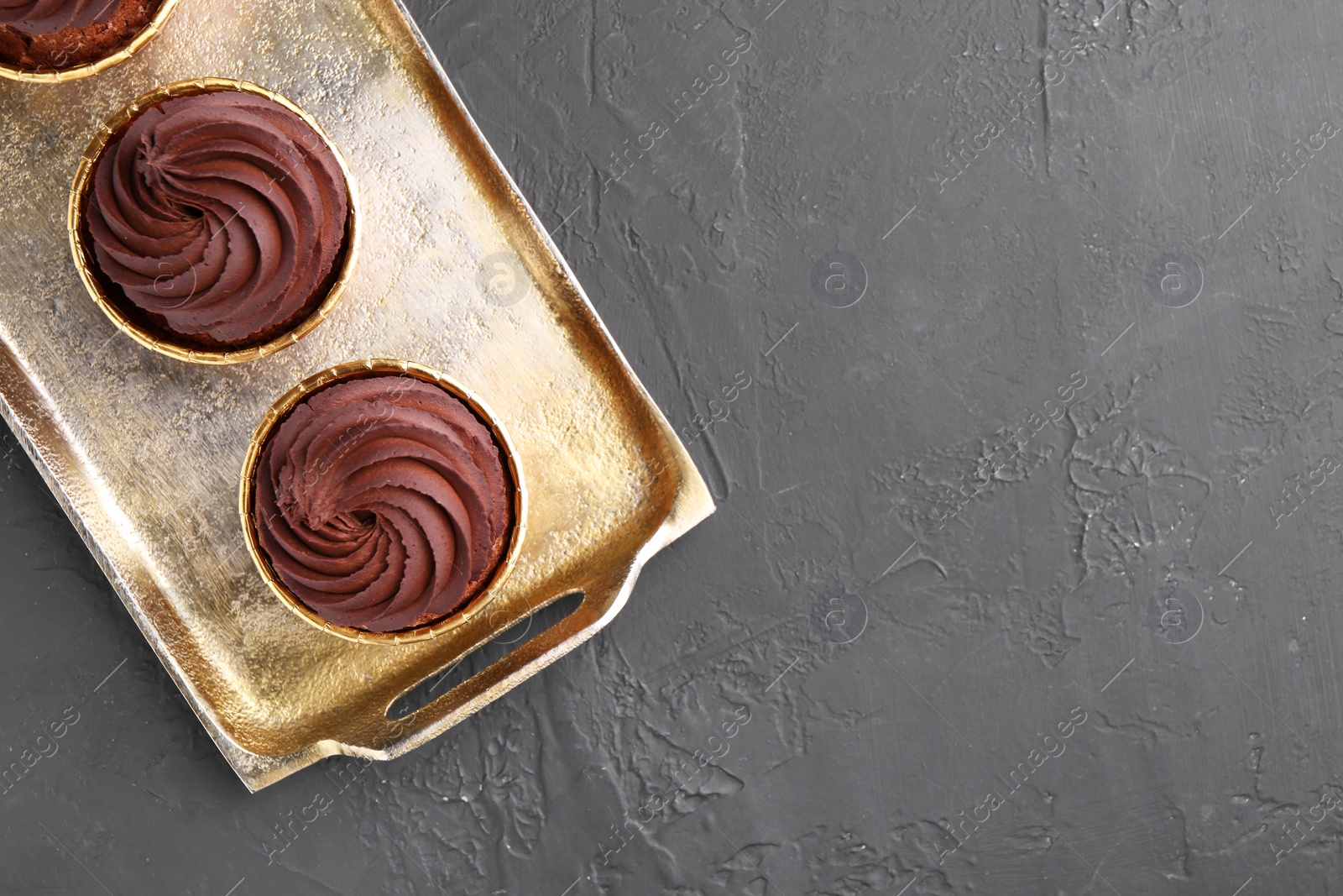 Photo of Delicious chocolate cupcakes on black textured table, top view. Space for text