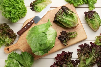Photo of Different sorts of lettuce and knife on white wooden table, flat lay