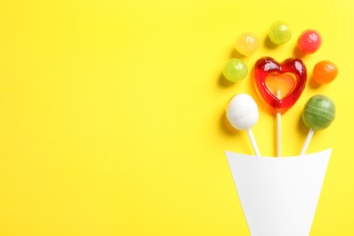 Photo of Flat lay composition with hard candies on yellow background, space for text