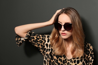Photo of Young woman wearing stylish sunglasses on dark grey background