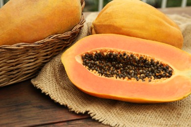 Tasty whole and cut papaya fruits on wooden table, closeup