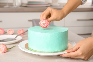 Woman decorating fresh delicious birthday cake in kitchen, closeup