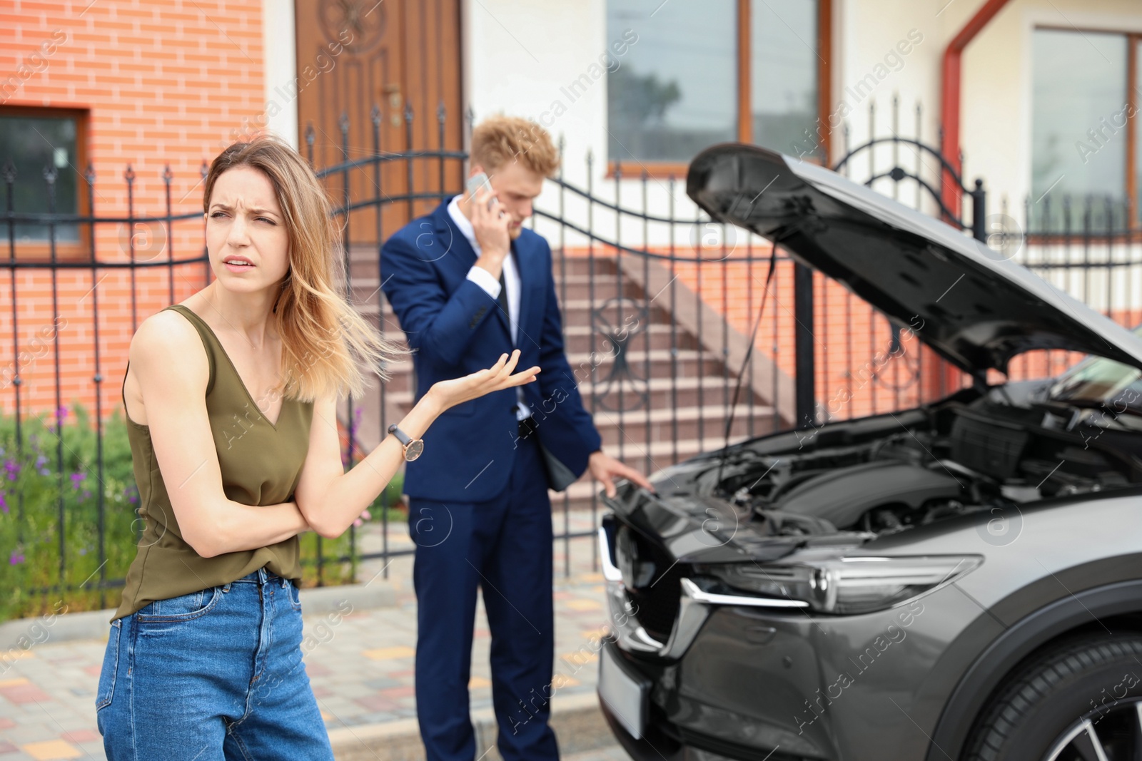 Photo of Young man and woman near broken car outdoors