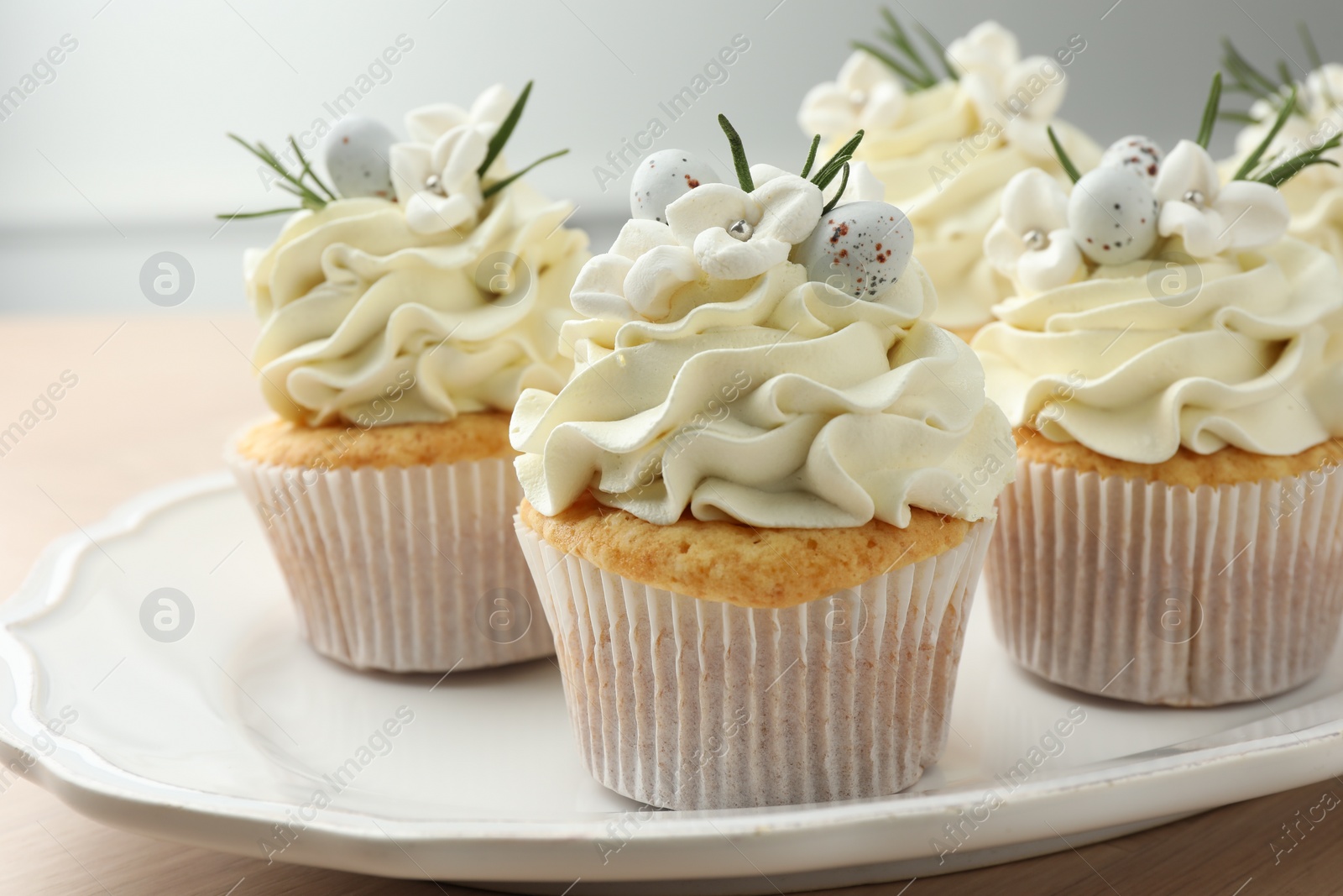 Photo of Tasty Easter cupcakes with vanilla cream on table, closeup