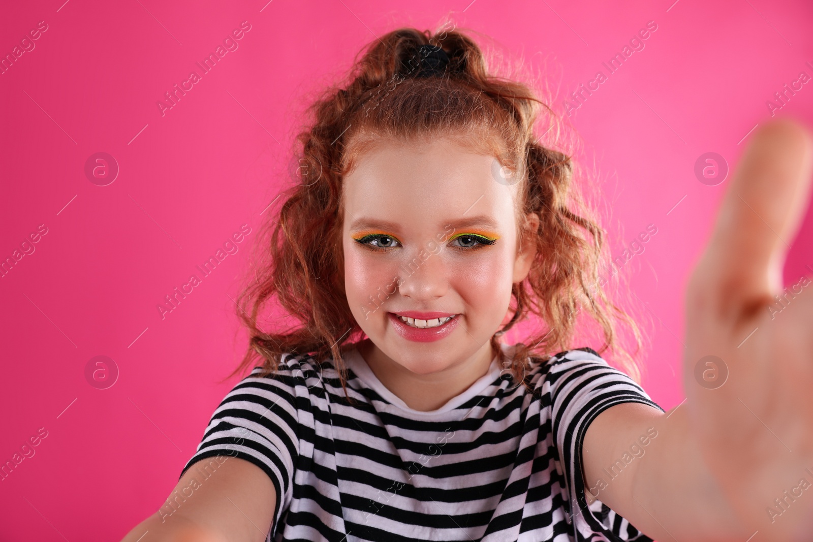 Photo of Cute indie girl taking selfie on pink background