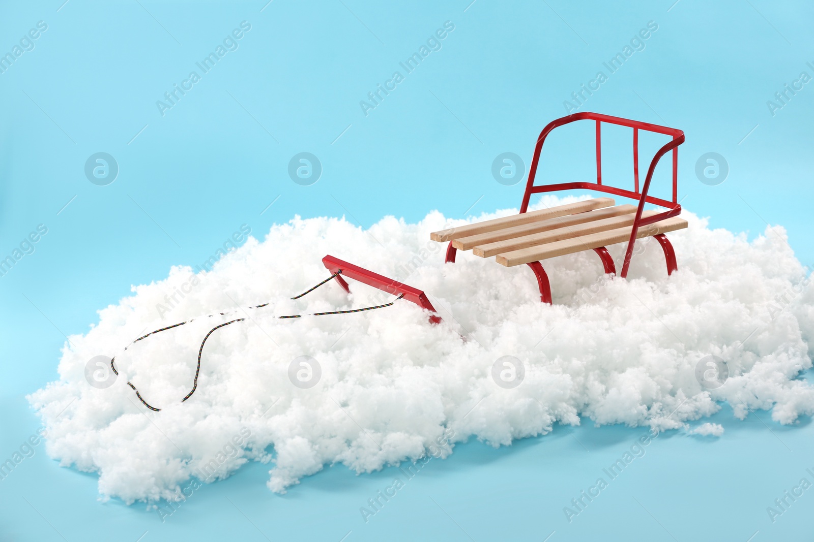 Photo of Empty sleigh in artificial snow on light blue background. Winter activity