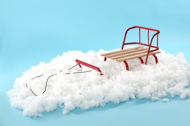 Photo of Empty sleigh in artificial snow on light blue background. Winter activity