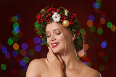 Beautiful young woman wearing Christmas wreath on blurred background. Bokeh effect