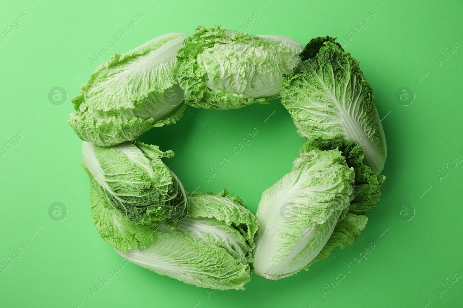 Photo of Frame with fresh ripe Chinese cabbages on light green background, flat lay. Space for text