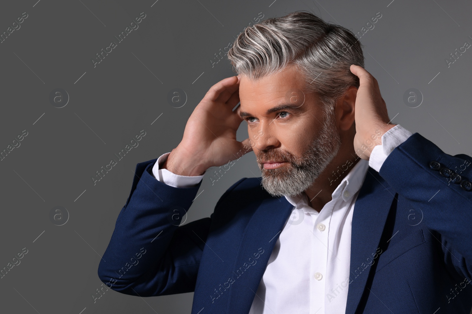 Photo of Portrait of confident man with beautiful hairstyle on dark grey background