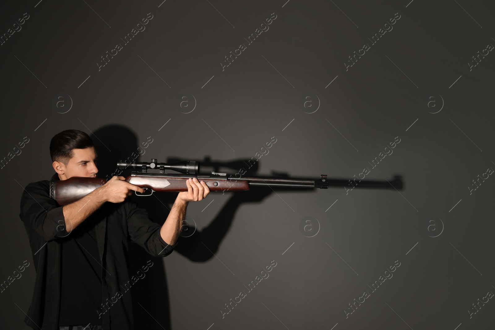 Photo of Professional killer with sniper rifle on black background