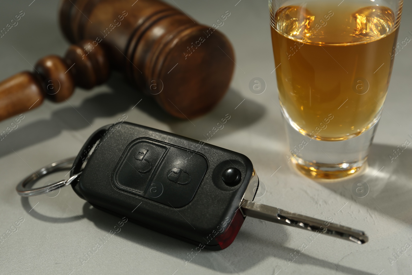 Photo of Car key, gavel near alcohol on table, closeup. Dangerous drinking and driving