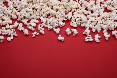 Tasty popcorn on red background, flat lay. Space for text