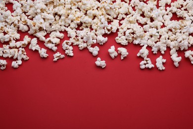 Photo of Tasty popcorn on red background, flat lay. Space for text