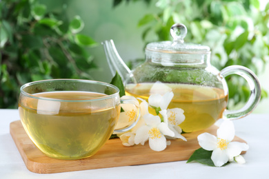 Tasty tea and fresh jasmine flowers on white wooden table