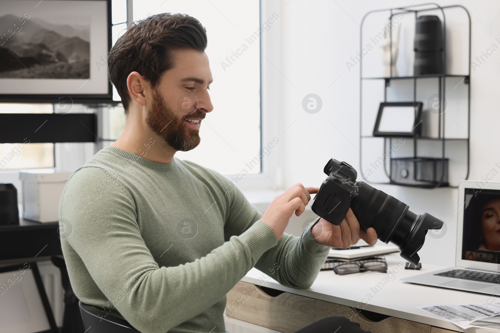 Photo of Professional photographer with digital camera at table in office