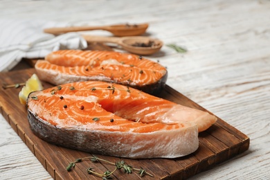 Photo of Fresh raw salmon steaks with seasonings on wooden board, closeup