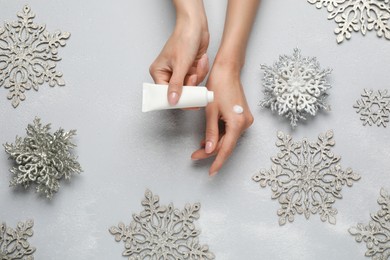 Photo of Woman applying cream onto hand on light grey background, top view