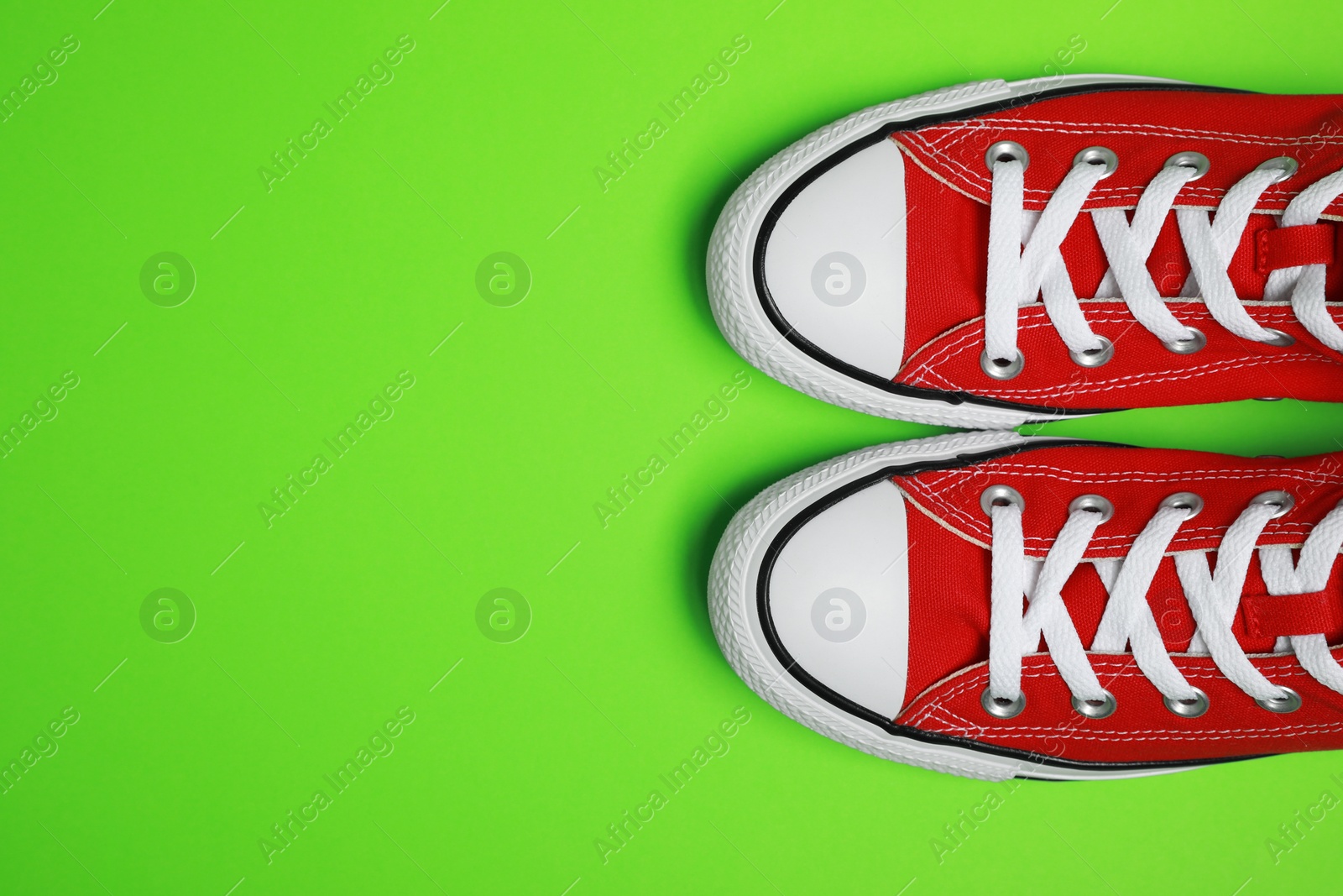 Photo of Pair of new stylish red sneakers on light green background, flat lay. Space for text