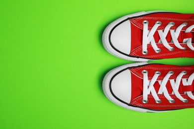 Photo of Pair of new stylish red sneakers on light green background, flat lay. Space for text