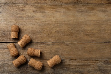 Photo of Sparkling wine corks on wooden table, flat lay. Space for text