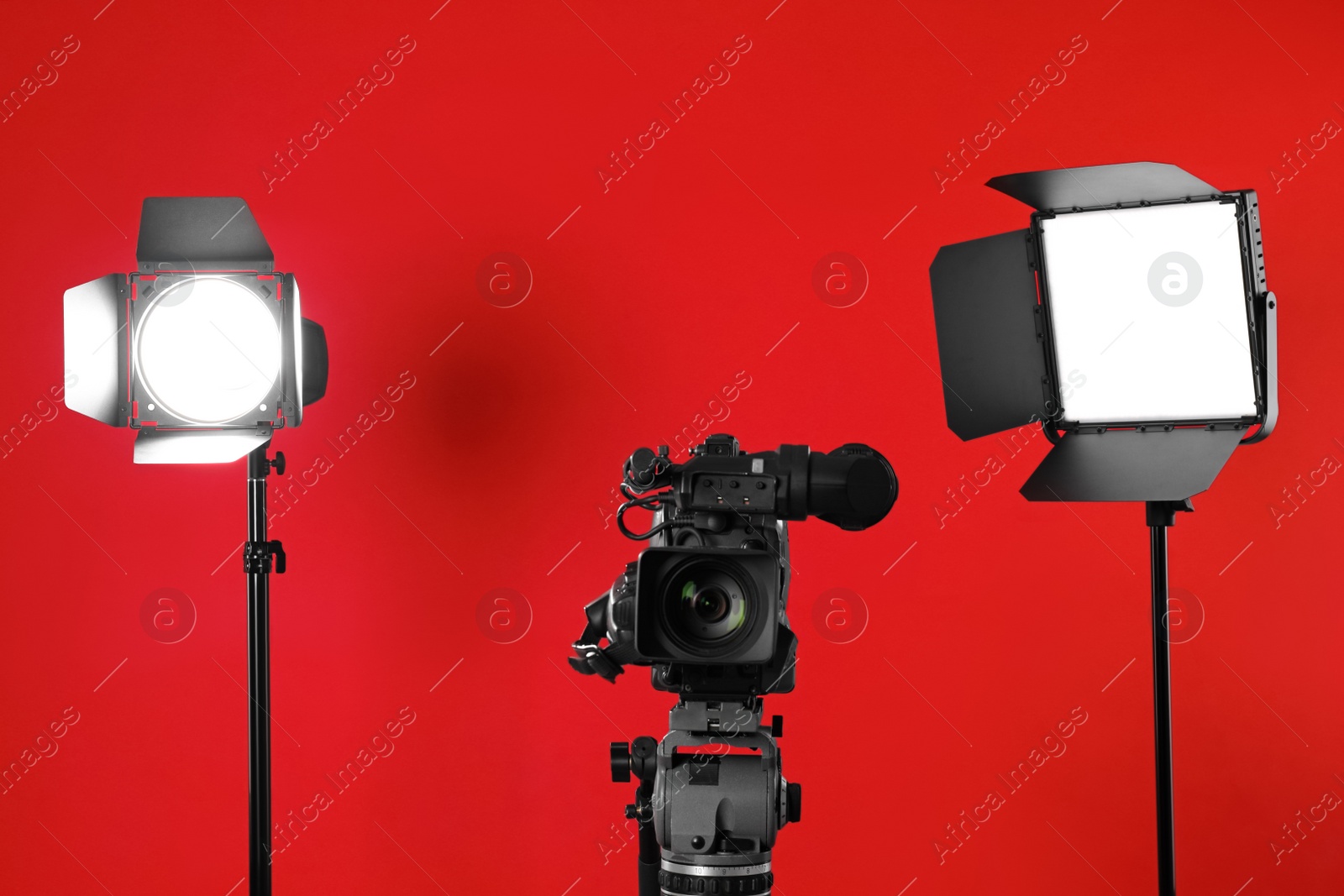 Photo of Professional video camera and lighting equipment on red background