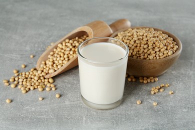 Glass with fresh soy milk and grains on grey table