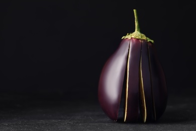 Photo of Cut purple eggplant on black slate table, closeup. Space for text