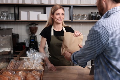 Photo of Seller giving customer fresh pastries in bakery shop