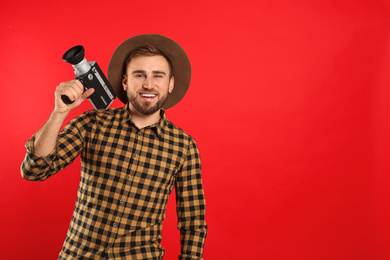 Young man with vintage video camera on red background. Space for text