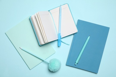 Pens and notebooks on light blue background, flat lay