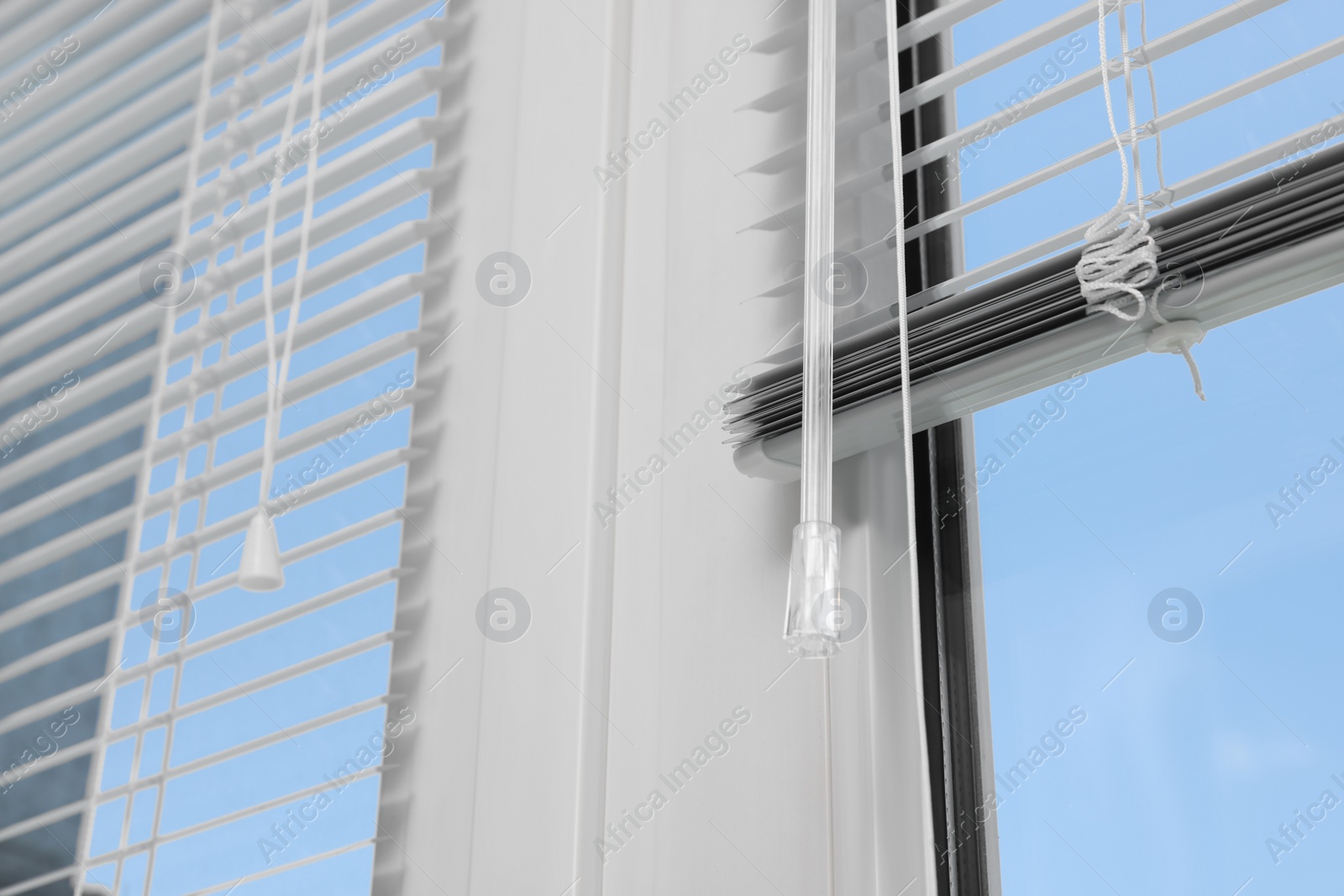 Photo of Window with horizontal blinds and control system indoors, closeup