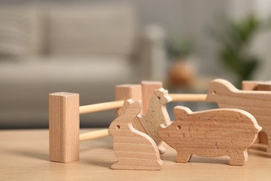 Wooden animals and fence on table indoors, closeup. Children's toys