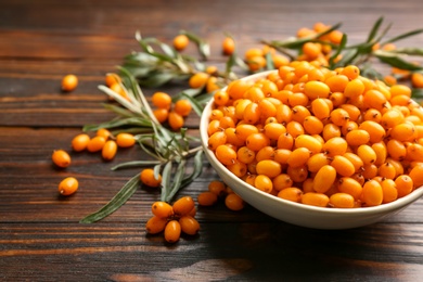 Photo of Fresh ripe sea buckthorn on wooden table. Space for text