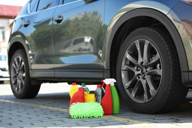 Car cleaning products and rag near automobile outdoors on sunny day