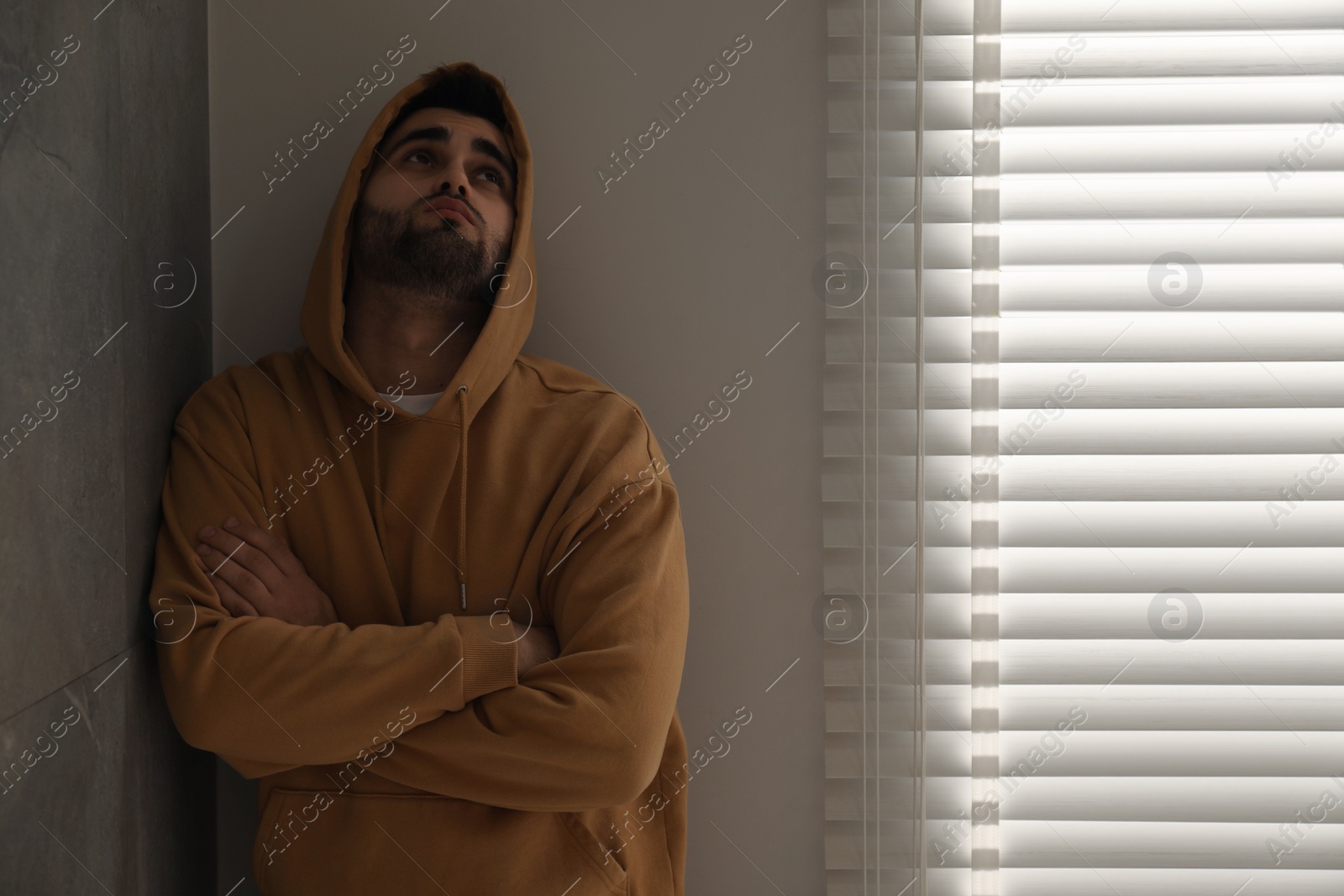 Photo of Sad young man at home. Space for text