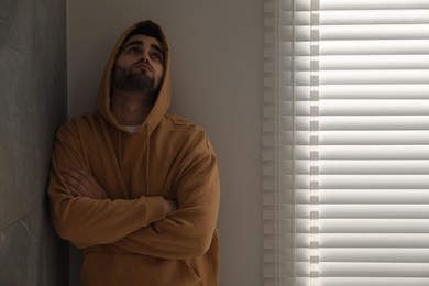 Photo of Sad young man at home. Space for text