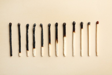 Photo of Row of burnt matches and whole one on color background, flat lay. Human life phases concept